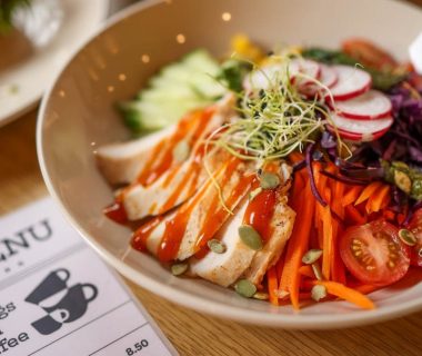 A vibrant salad bowl featuring fresh vegetables and grilled chicken on a wooden table.