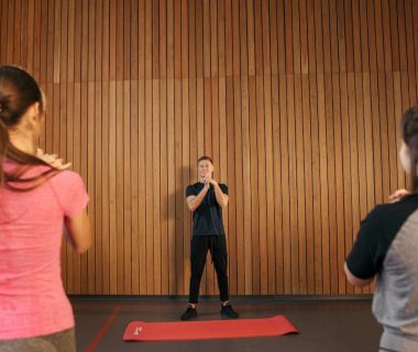 Fitness instructor leading a training session with two women in a modern gym setting.